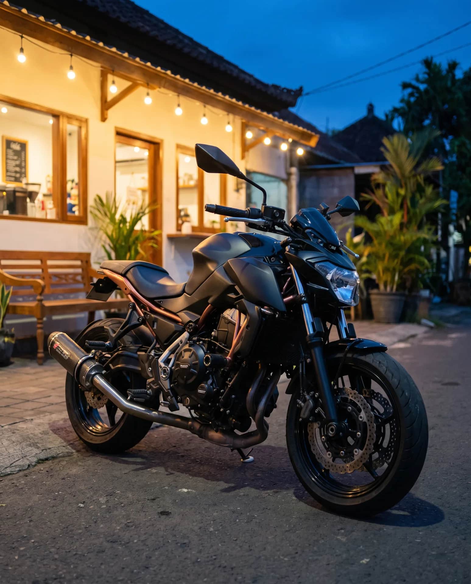 Kawasaki Z650 parked outside a Bali warung at dusk under string lights