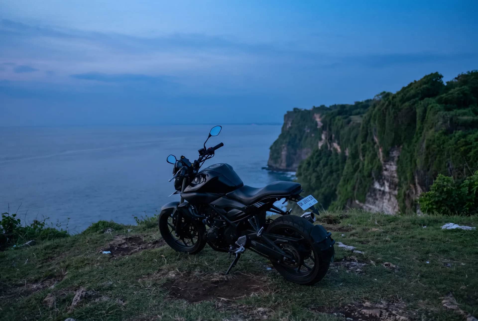 Yamaha MT-25 scrambler on a clifftop at blue hour overlooking the Bali coast
