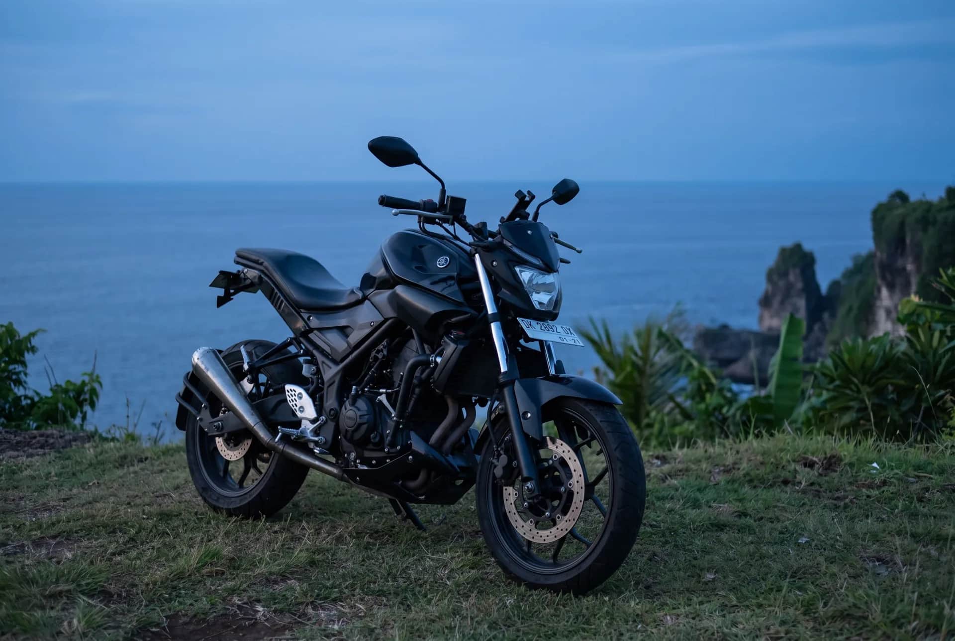 Yamaha MT-25 scrambler at dusk above the ocean and sea cliffs in Bali