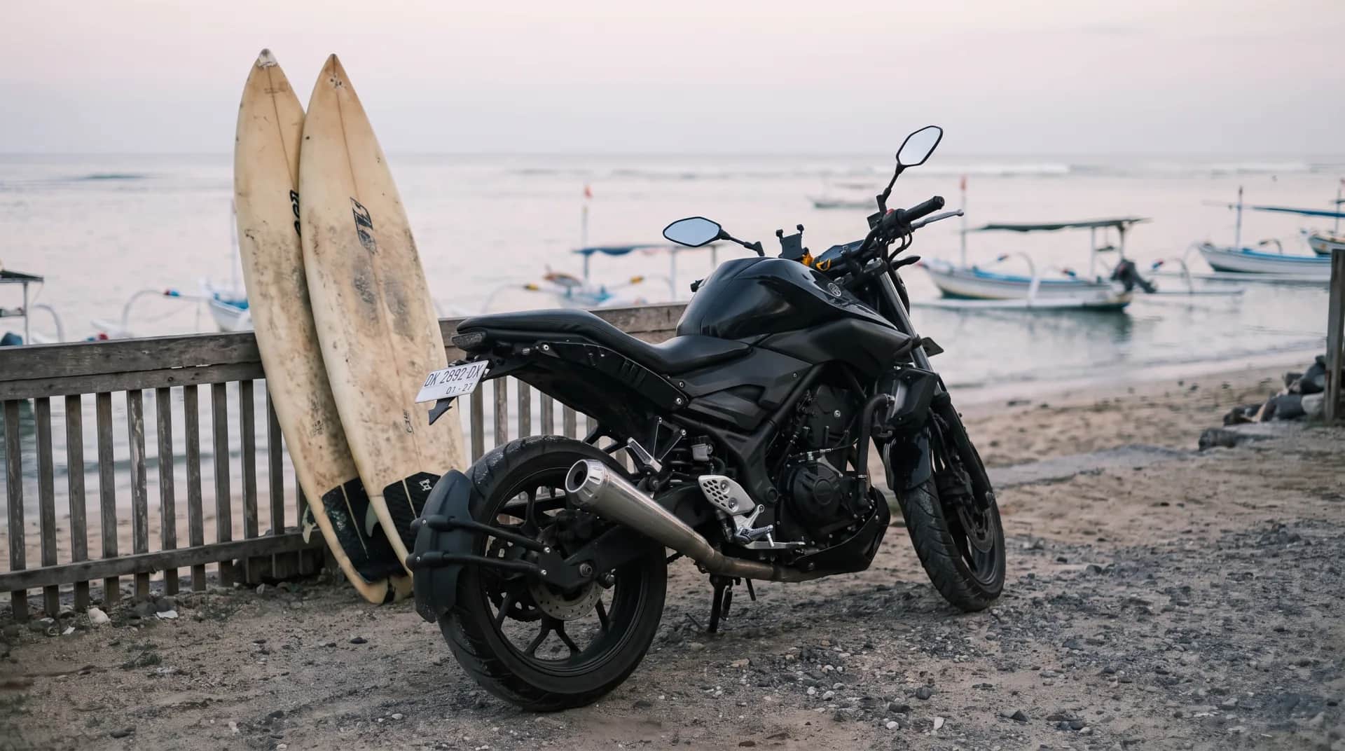 Yamaha MT-25 scrambler beside surfboards at a Bali beach