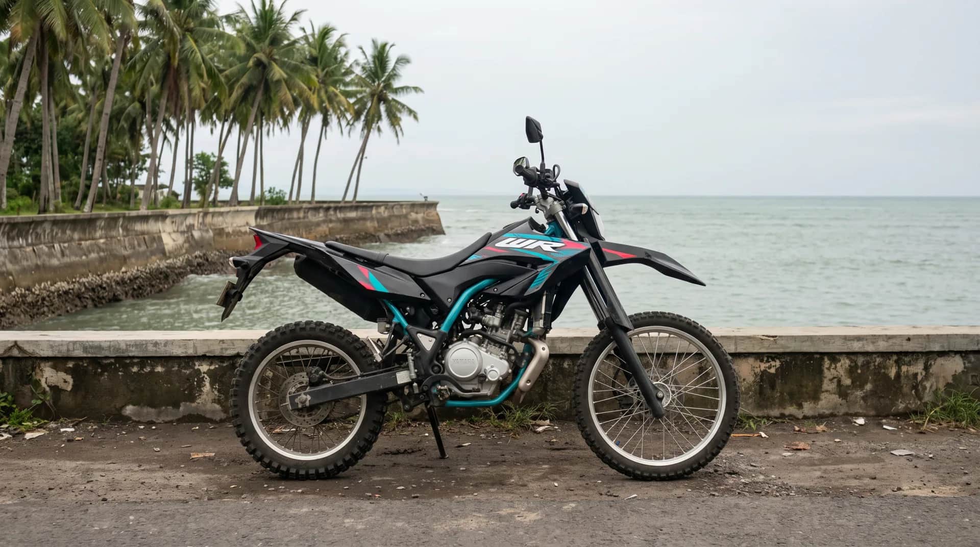 Side profile of the Yamaha WR155 trail bike on a coastal seawall in Bali
